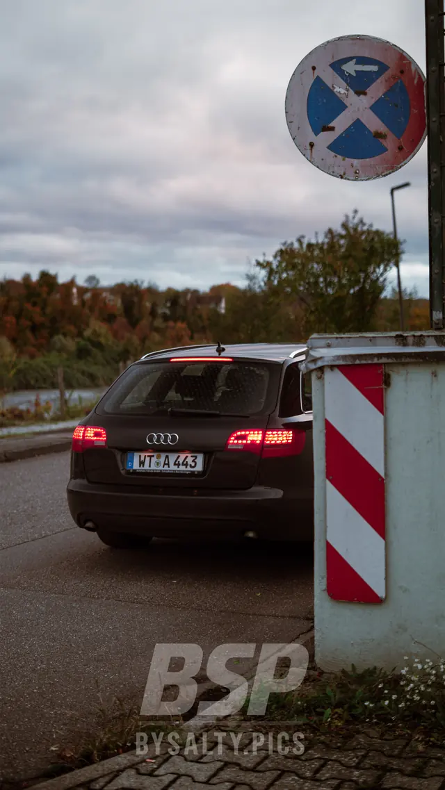 Audi A6 Avant von hinten mit leuchtenden Rücklichtern neben einer Warnbake