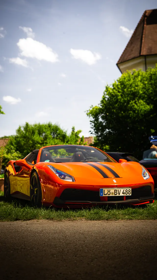 Oranger Sportwagen mit schwarzen Rennstreifen auf einem Car Meet