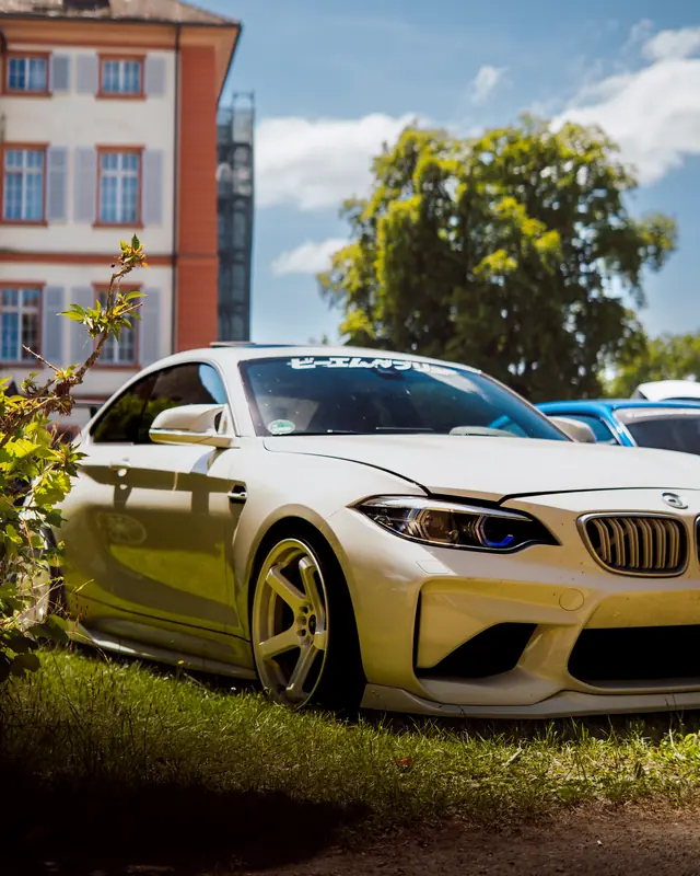 Weißer BMW M2 mit goldenen Felgen auf einem Car Meet