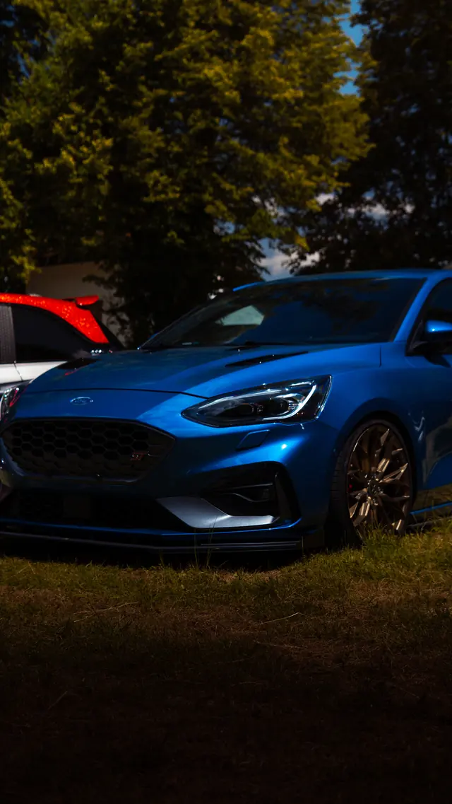 Blauer Ford Focus mit goldenen Felgen im Gras auf einem Car Meet