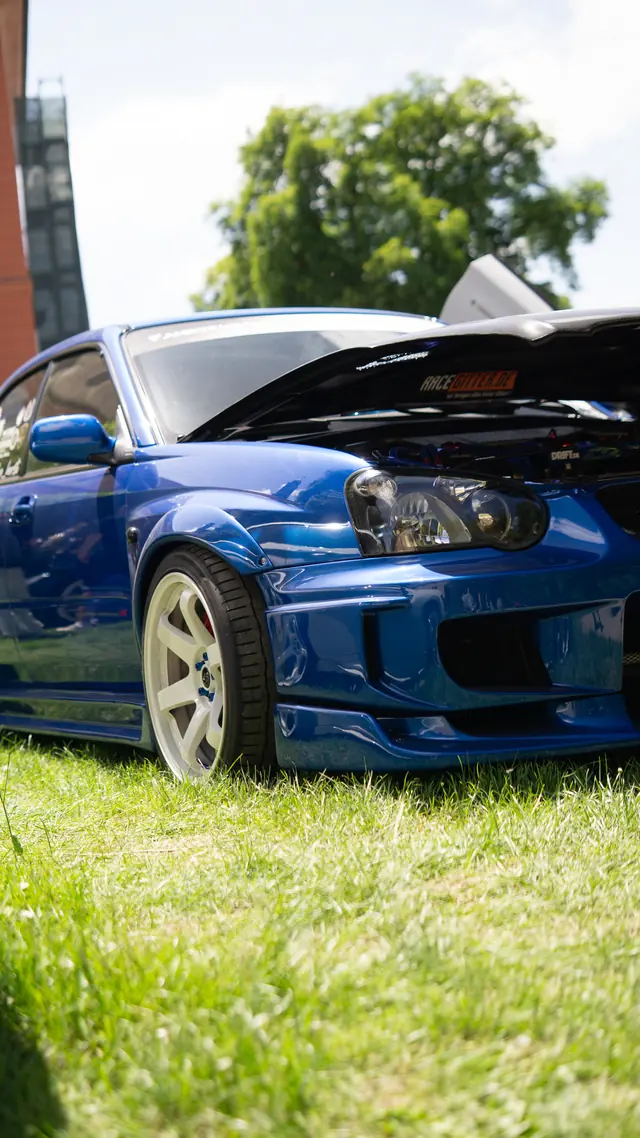 Blauer Subaru Impreza mit geöffneter Motorhaube auf einer Wiese