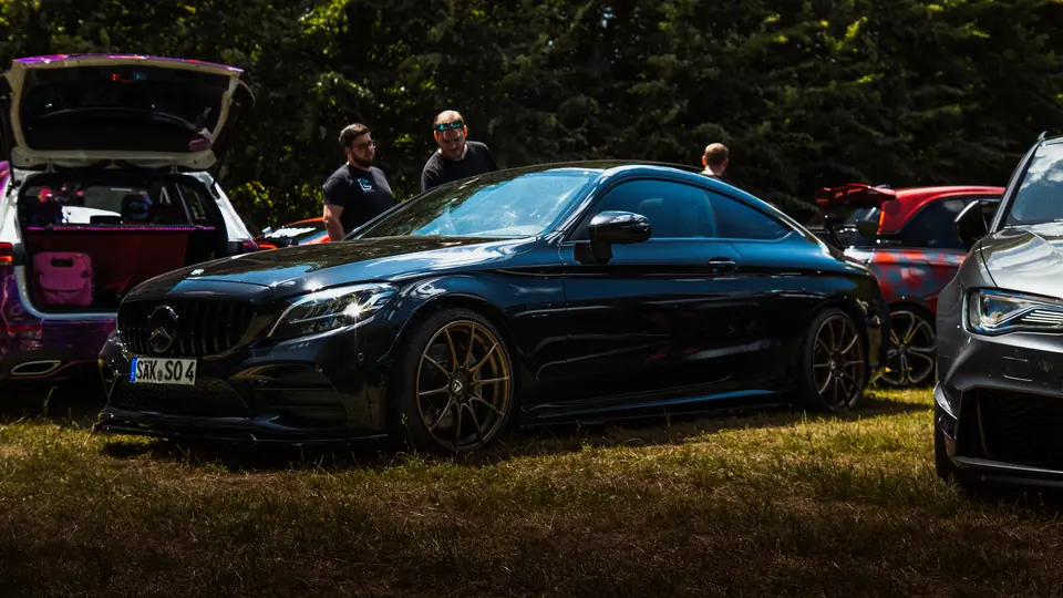 Schwarzes Mercedes Coupé auf einer Wiese beim Car Meet