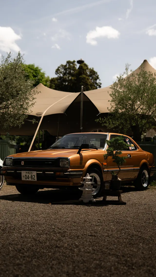 Goldbrauner japanischer Oldtimer vor einem Zelt auf einem Fahrzeugtreffen