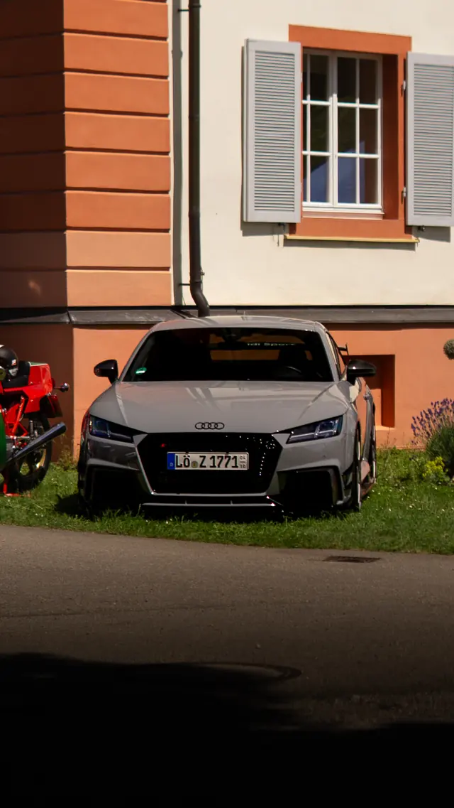 Grauer Audi TT vor einem Gebäude mit Fensterläden