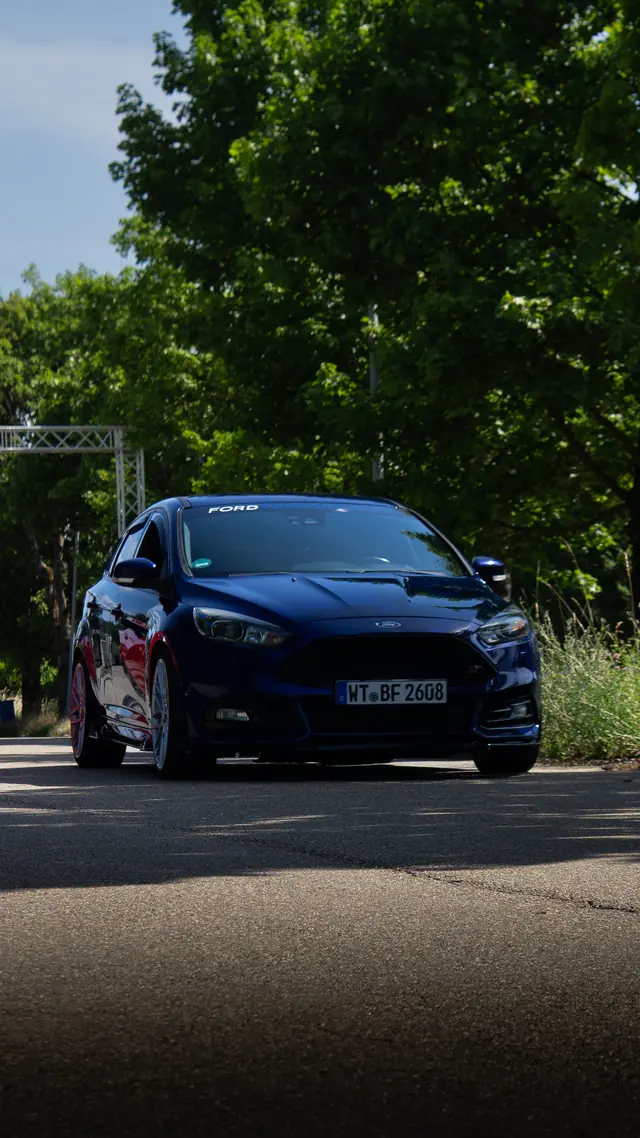 Dunkelblauer Ford Focus auf einer Straße im Sommer